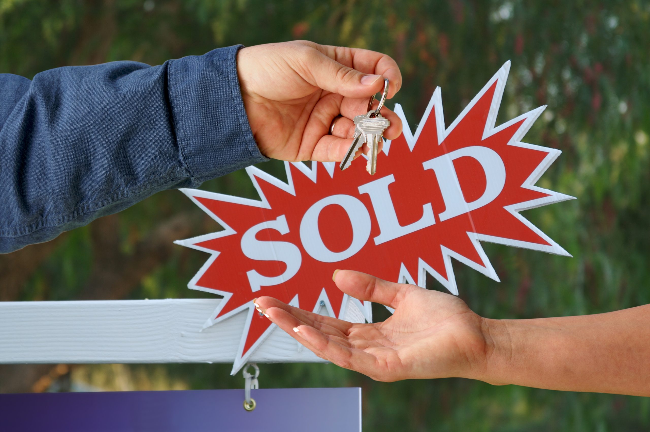 Sold sign and agent hands over key to buyer